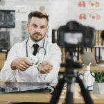 Doctor recording vlog with contactless thermometer in hands