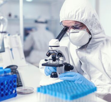 Focused healthcare researcher with face mask and ppe analysing covid