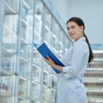 Pharmacist posing for the camera among shelves with healthcare products
