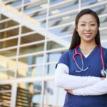 Smiling Asian female healthcare worker with arms crossed